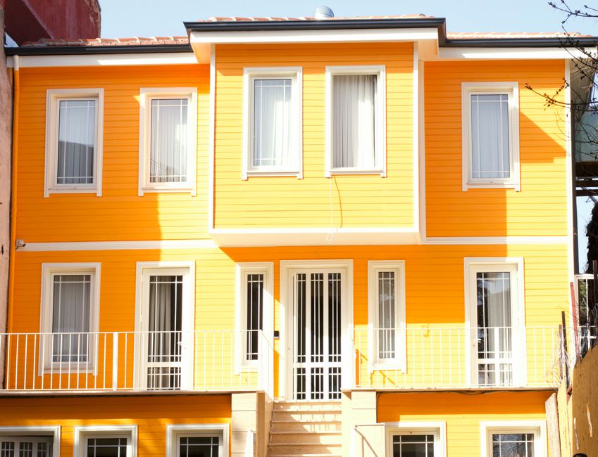 Painted house front with window trim and a wooden door